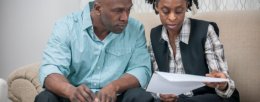 A husband and wife are sitting in their home looking over their finances and are working on their retirement plan.