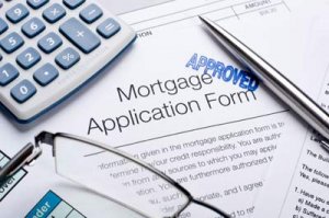 Approved mortgage application form with calculator, pen and reading glasses