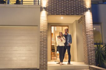 Couple standing in front of their new home.